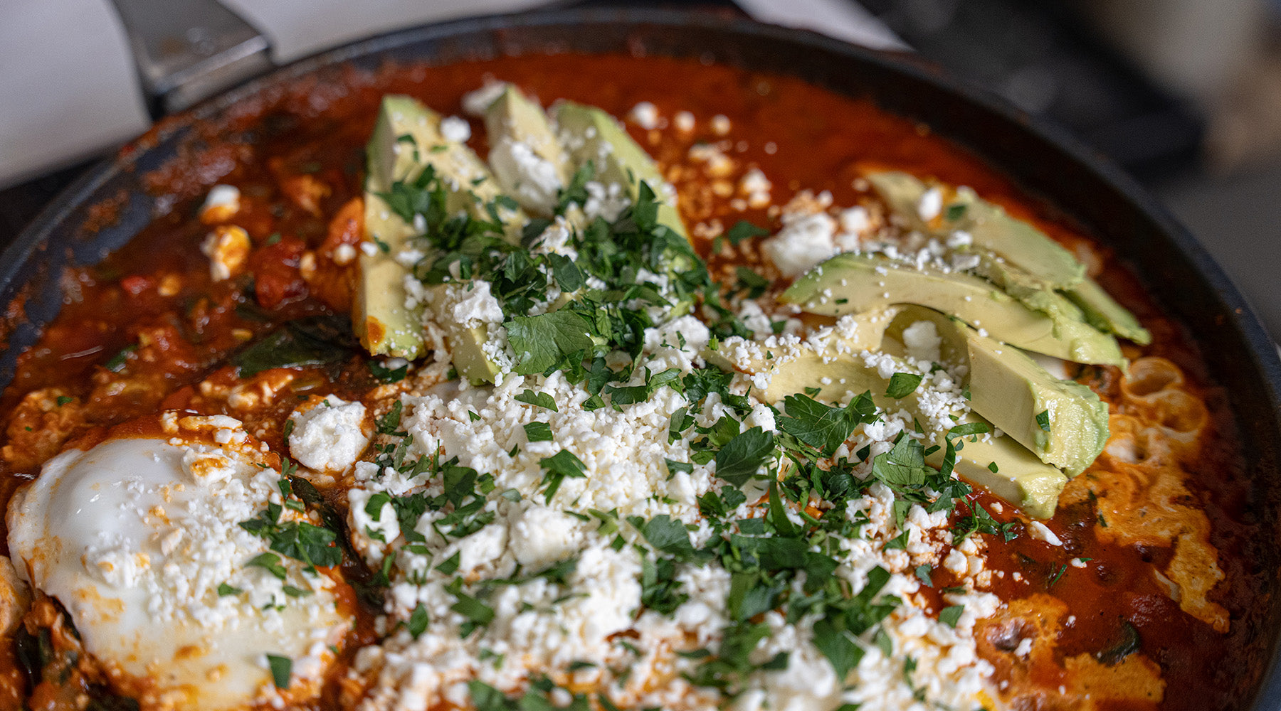Close up photo of shakshuka in a Swiss Diamond Fry pan with avocado and feta on top