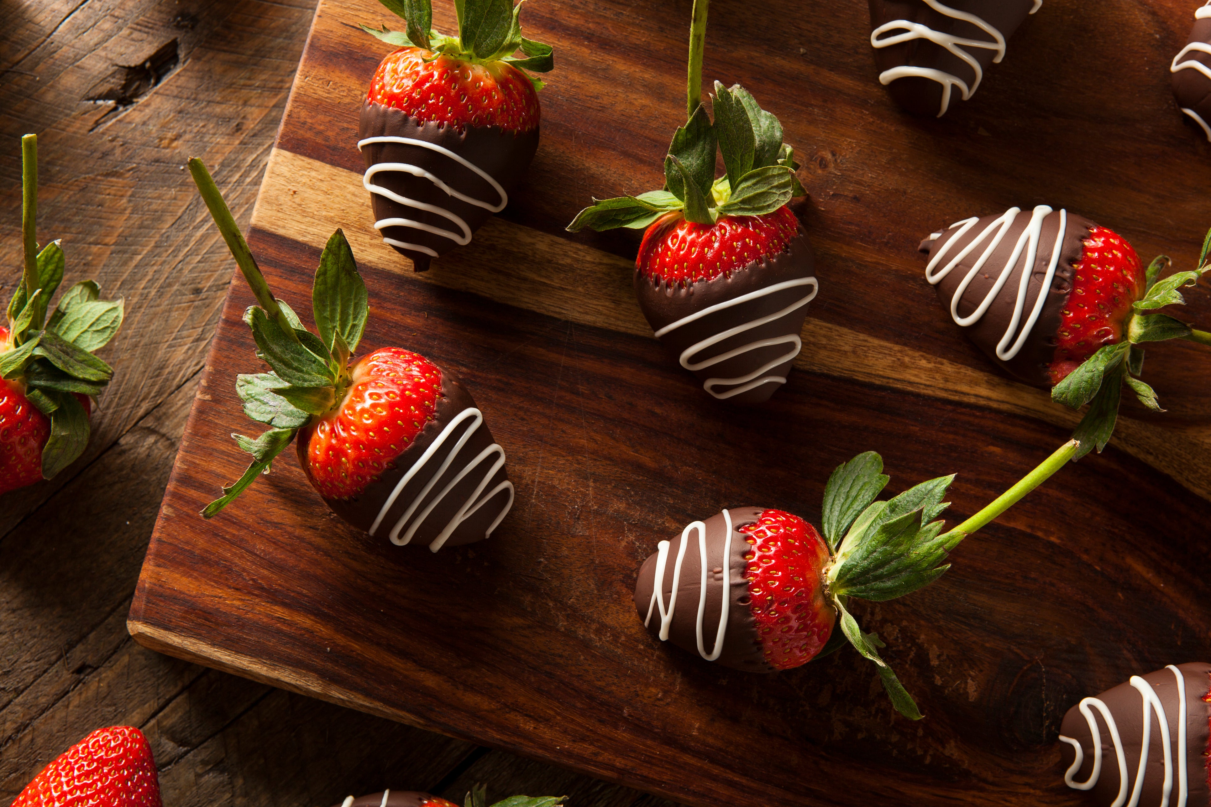 chocolate covered strawberries on a wood cutting board
