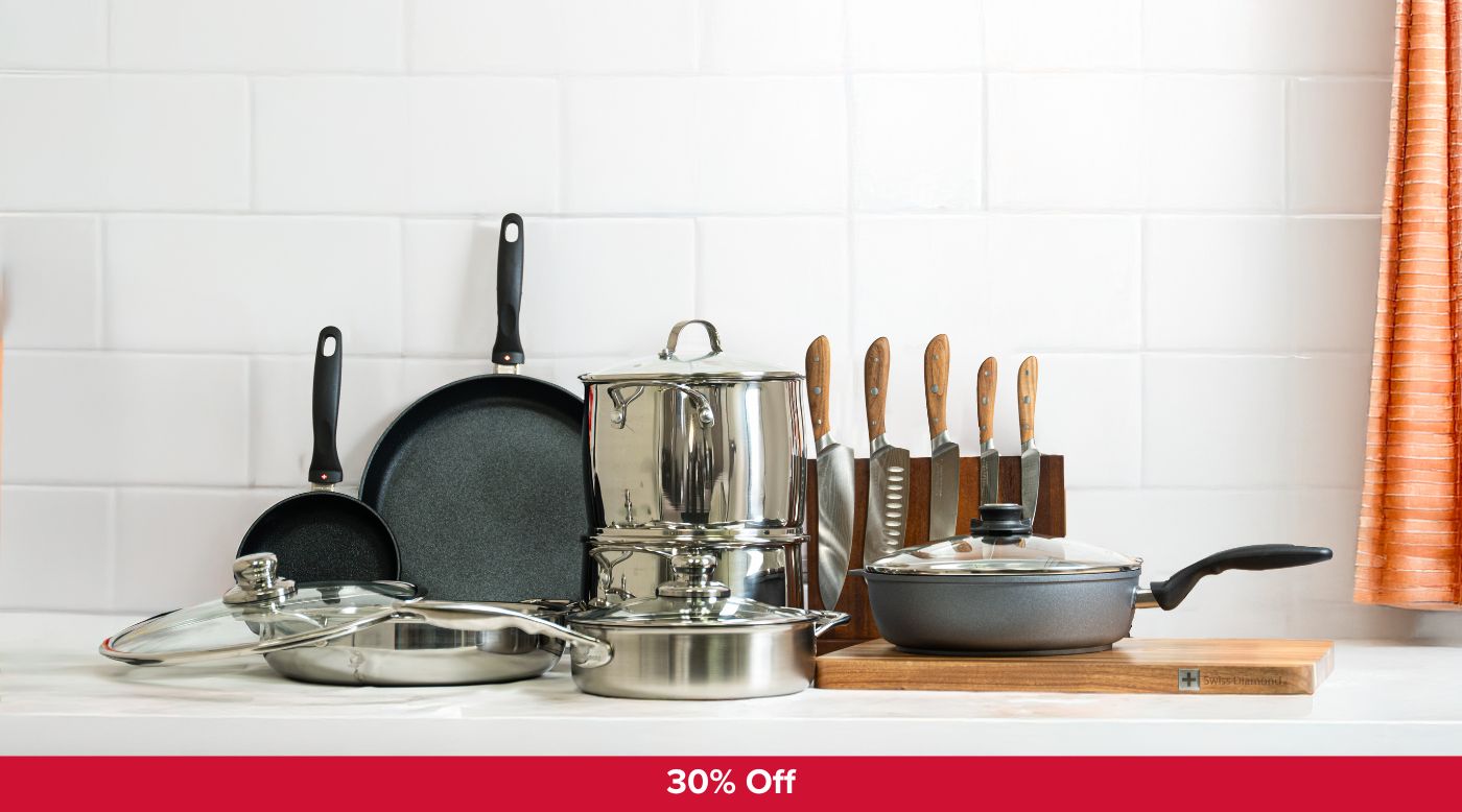 set of cookware including fry pans, saute pans, knives and dutch oven on white kitchen counter