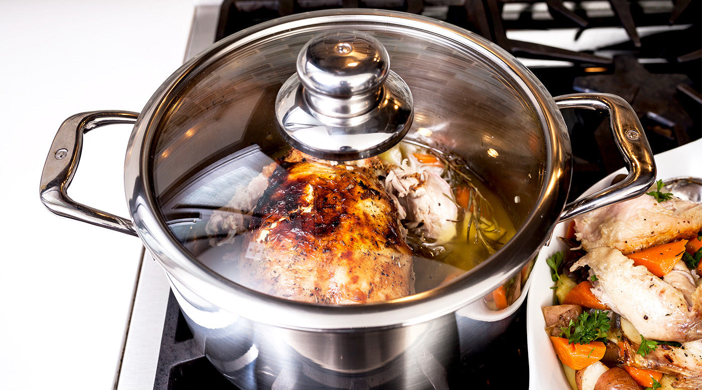 Stainless Steel Casseroles & Dutch Ovens with glass lid and food inside on a gas stovetop