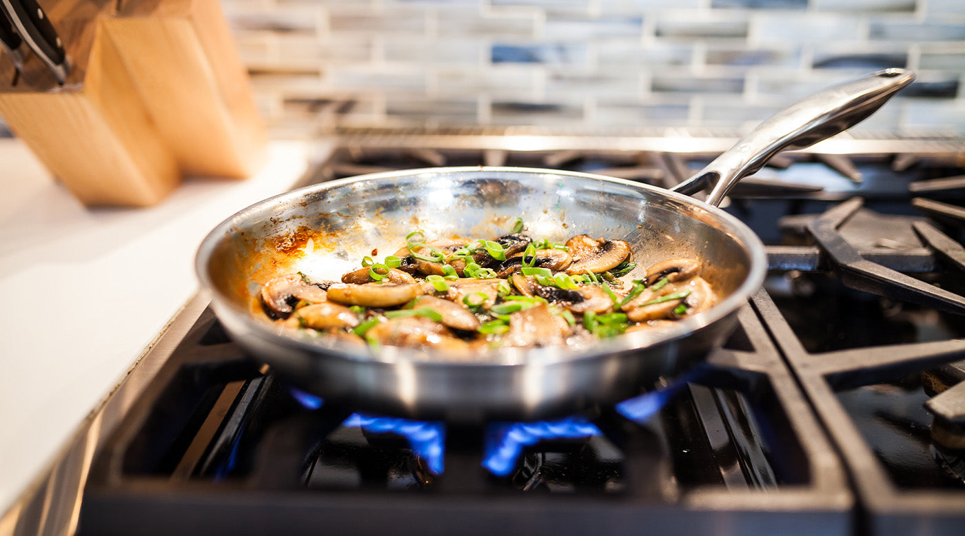 Stainless Steel Fry Pans with food inside on gas stove top in kitchen