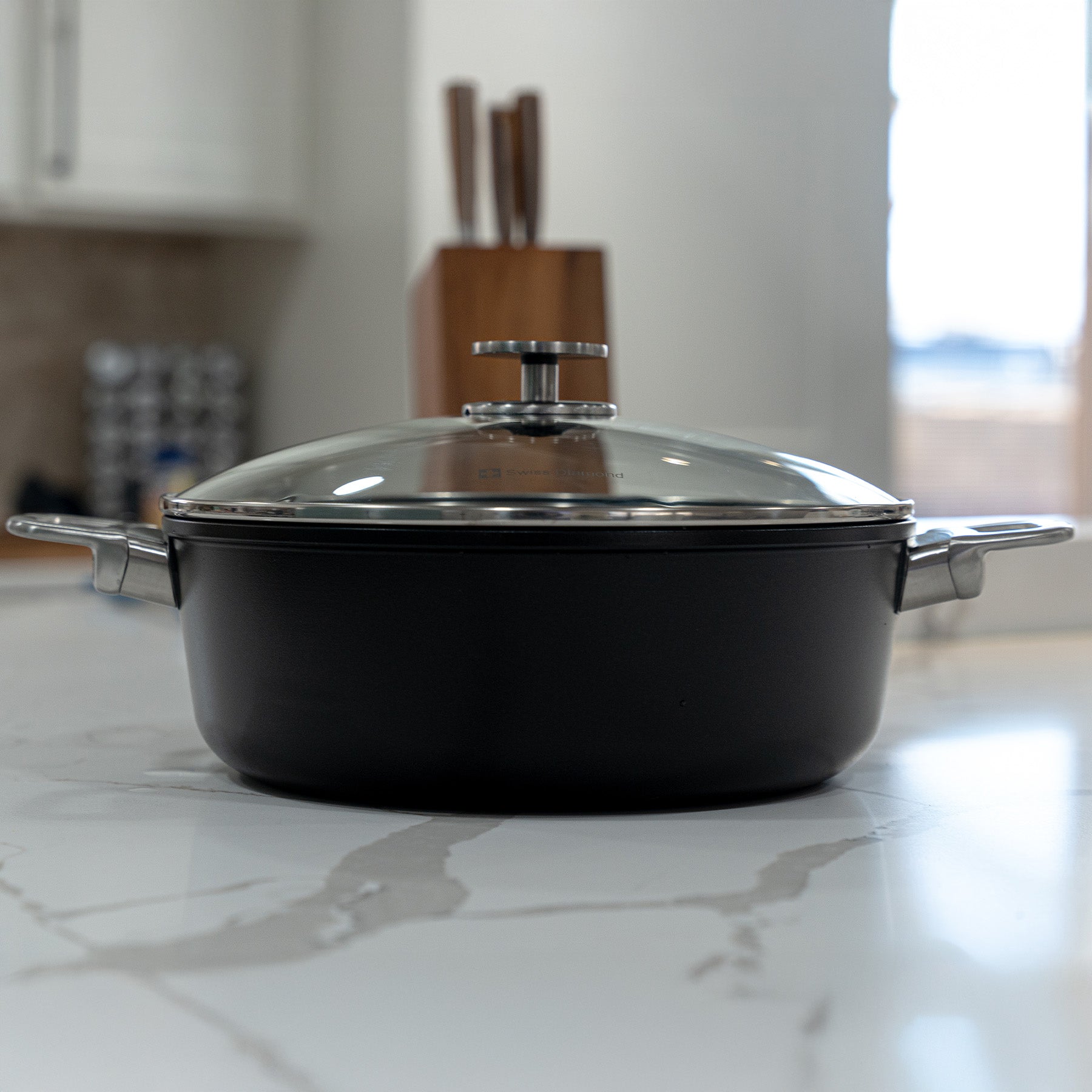 CHD Nonstick 5.3 qt Braiser with Glass Lid side view on white marble kitchen counter