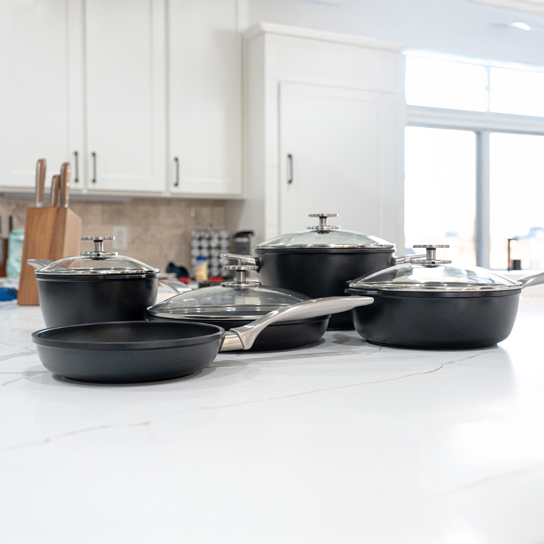 CHD Nonstick 9-Piece Set with 8" Fry Pan, 10.25" Fry Pan with Lid, 2.2 qt Saucepan with Lid, 5.5 qt Stock Pot with Lid and a 3.2 qt Saute Pan with Lid on white marble kitchen counter