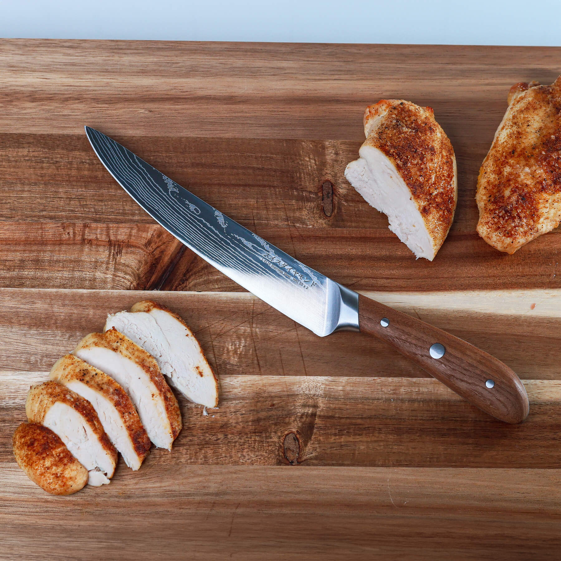 8" Damascus Carving Knife on cutting board with sliced chicken