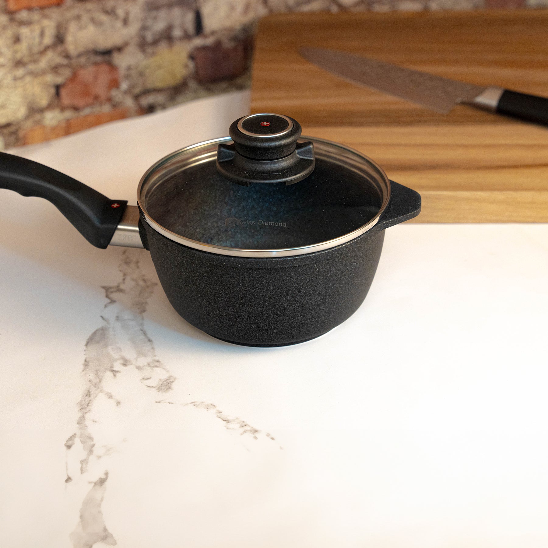 XD Nonstick Saucepan with Glass Lid side view with cutting board in background on kitchen counter