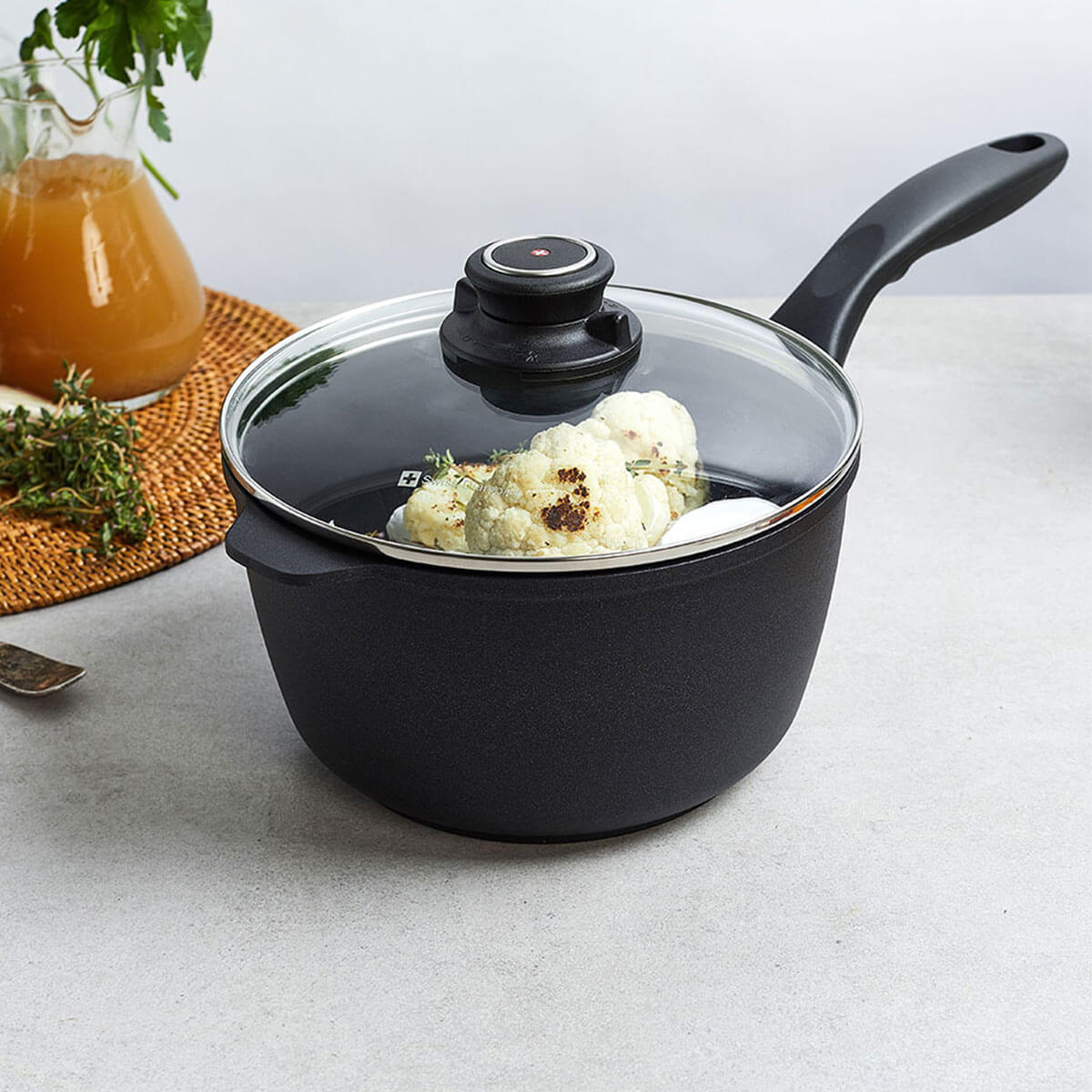 side view of a xd saucepan with glass lid with food inside on a kitchen counter