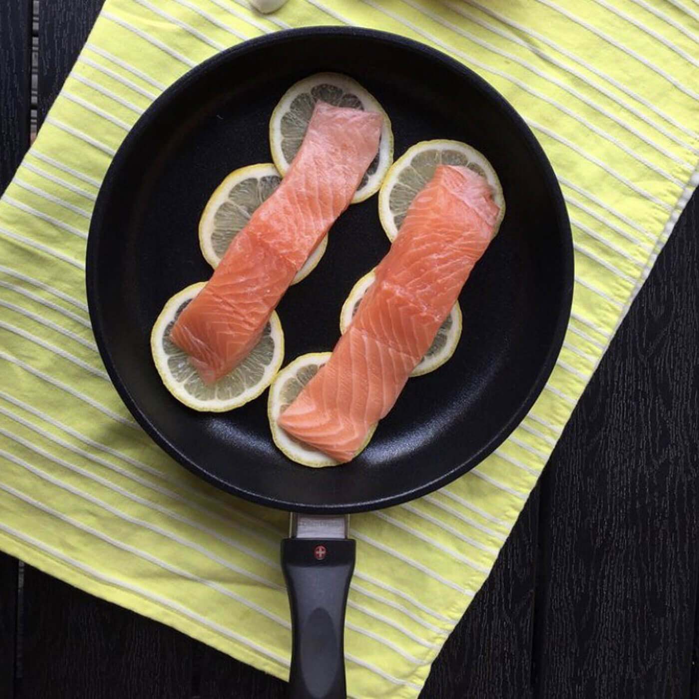 xd fry pan in use with lemon slices and salmon on wooden table