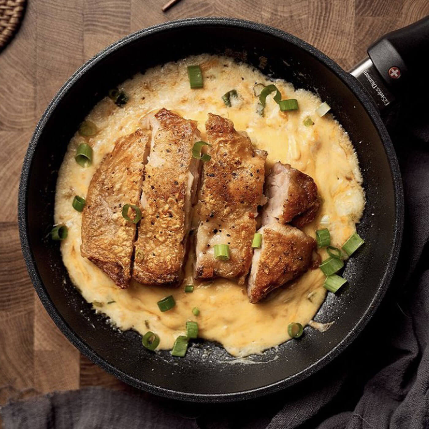 xd fry pan in use with sauce, cooked chicken, and chives on wooden table