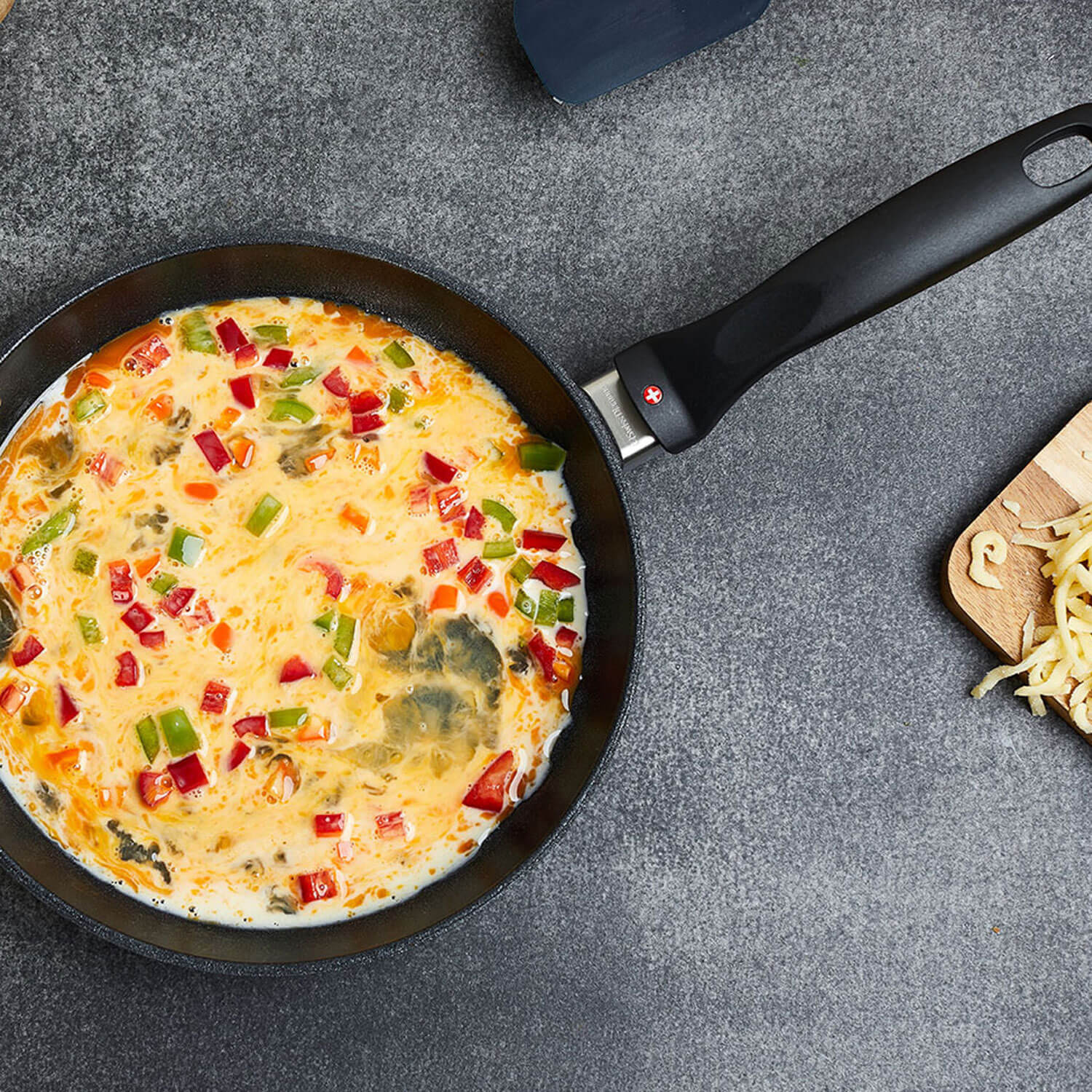 fry pan in use with egg mixture filled with veggies on a table