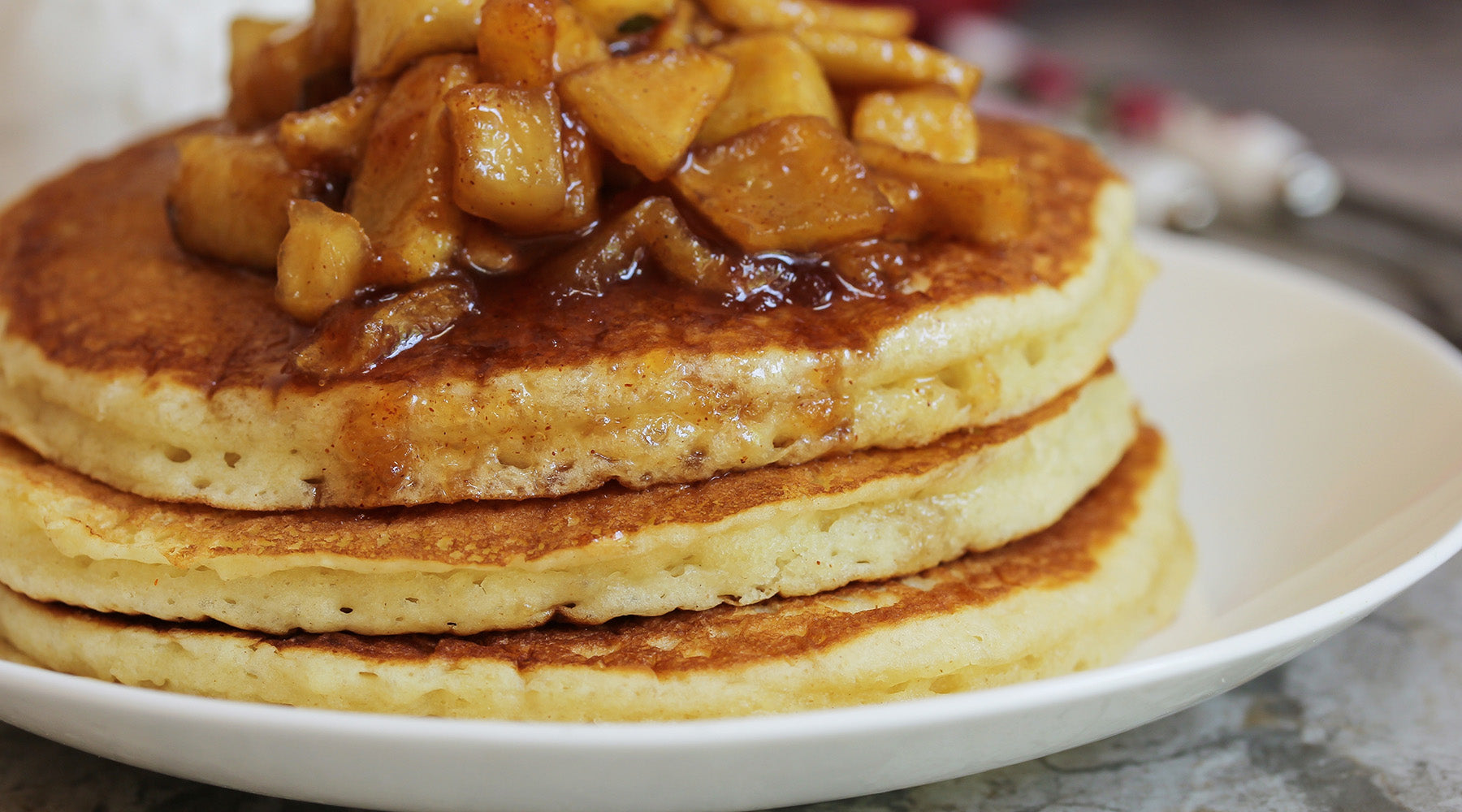 Stacked pancakes topped with chunks of apple