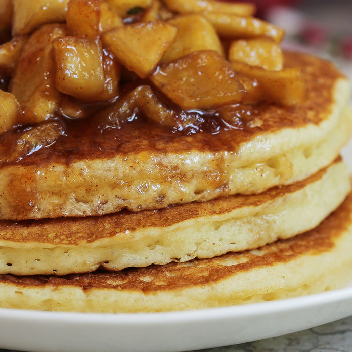 Stacked pancakes topped with chunks of apple