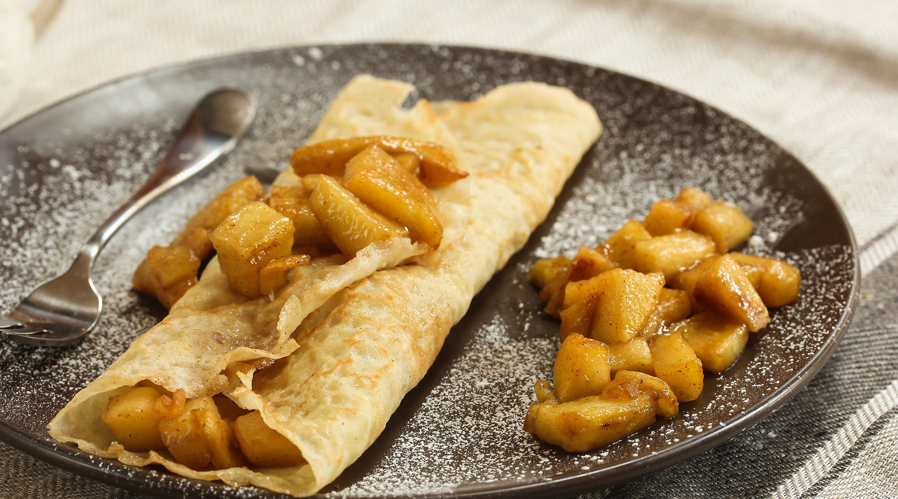 Apple crepe on a plate with apples on the side