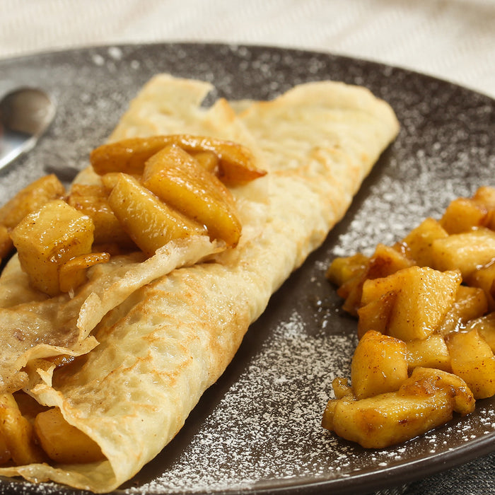 Apple crepe on a plate with apples on the side