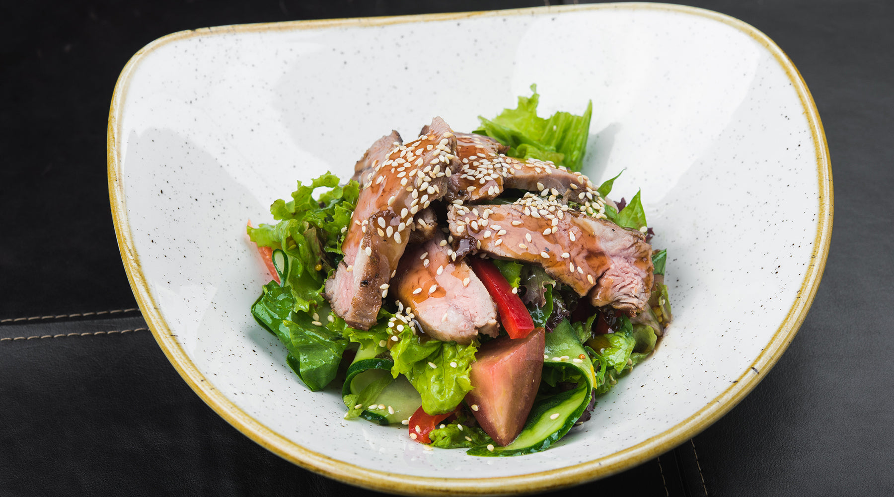 Asian Cucumber and Duck Salad in a white bowl topped with Sesame seeds