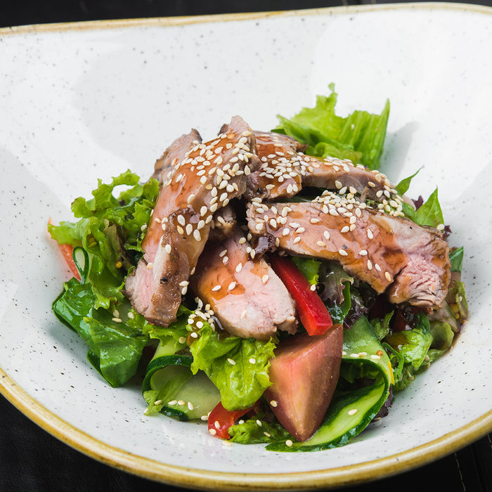 Asian Cucumber and Duck Salad in a white bowl topped with Sesame seeds