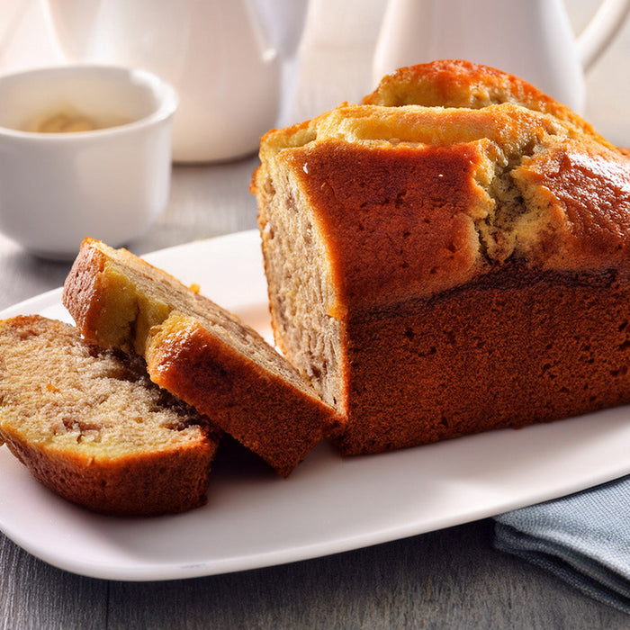 Sliced banana bread on a white plate with a coffee cup in the background