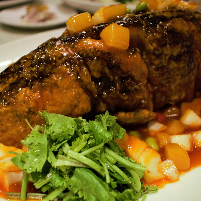 Barbeque pork topped with blistered chile-pumpkin seed salsa on a white plate