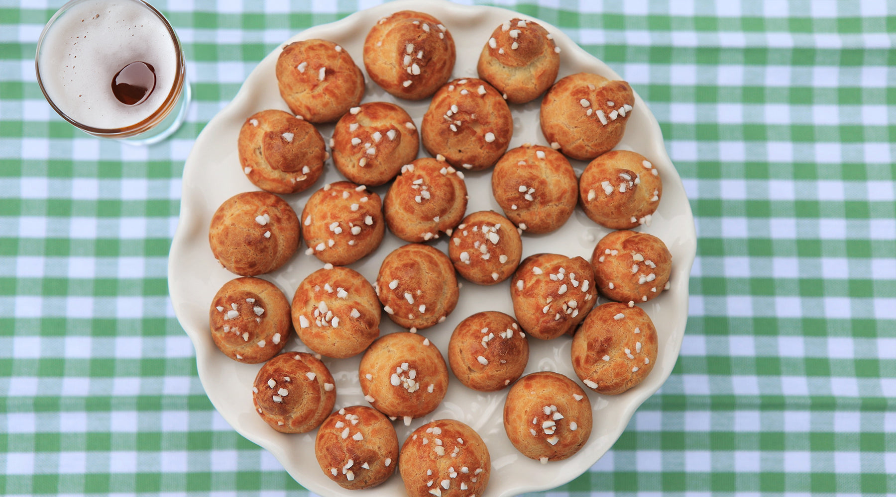 pretzel bites on a plate and a glass of beer to the left of the plate