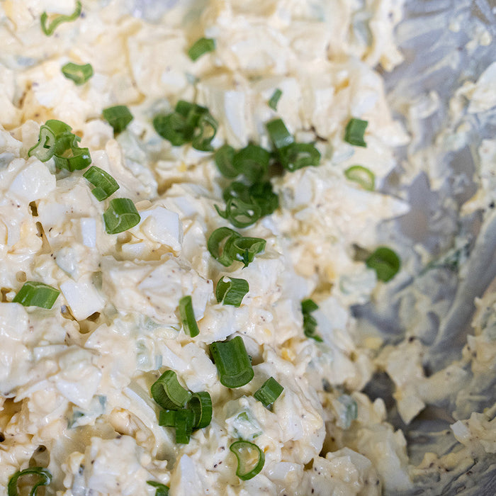 Egg salad in a bowl topped with green onion 