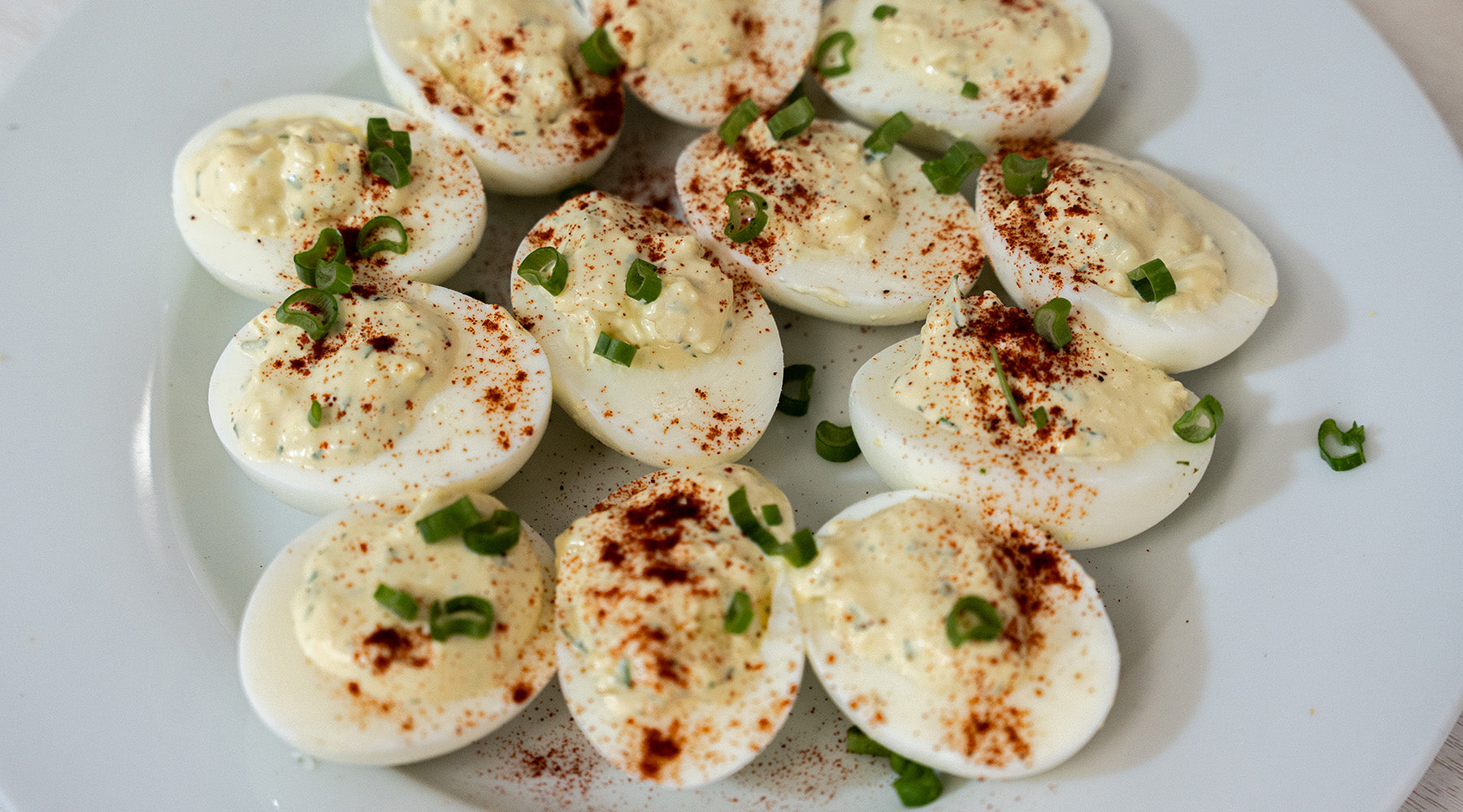 deviled eggs on a white plate topped with paprika