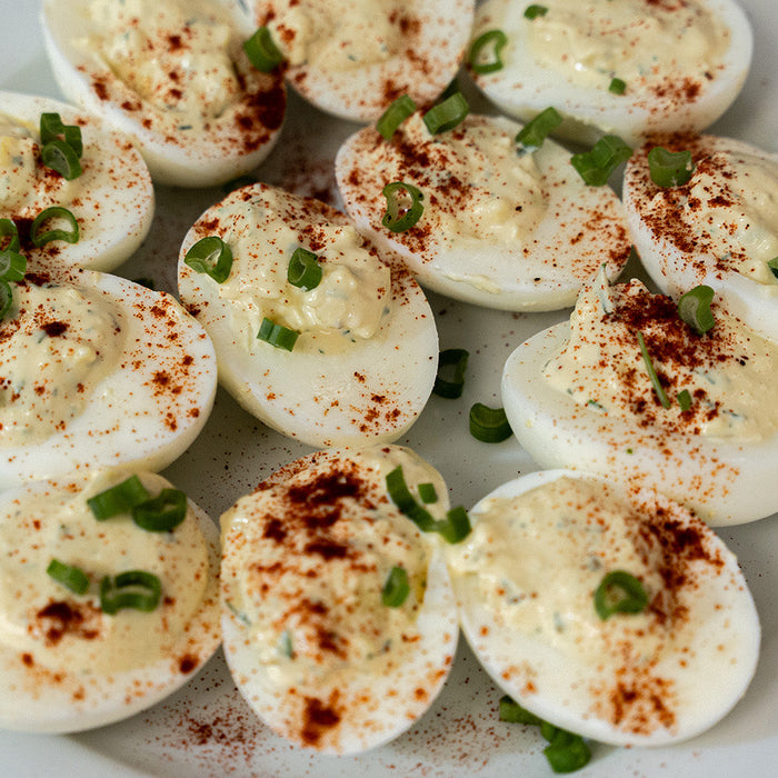 deviled eggs on a white plate topped with paprika
