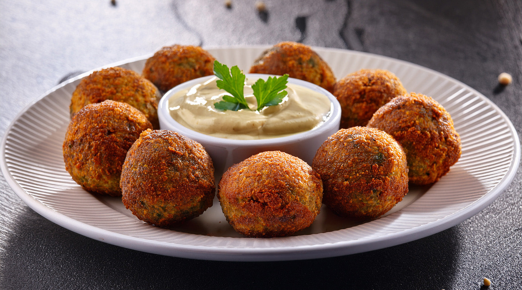 Falafel with a side of tahini sauce on a white plate