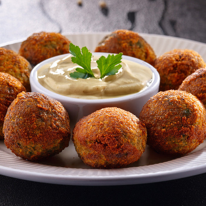 Falafel with a side of tahini sauce on a white plate
