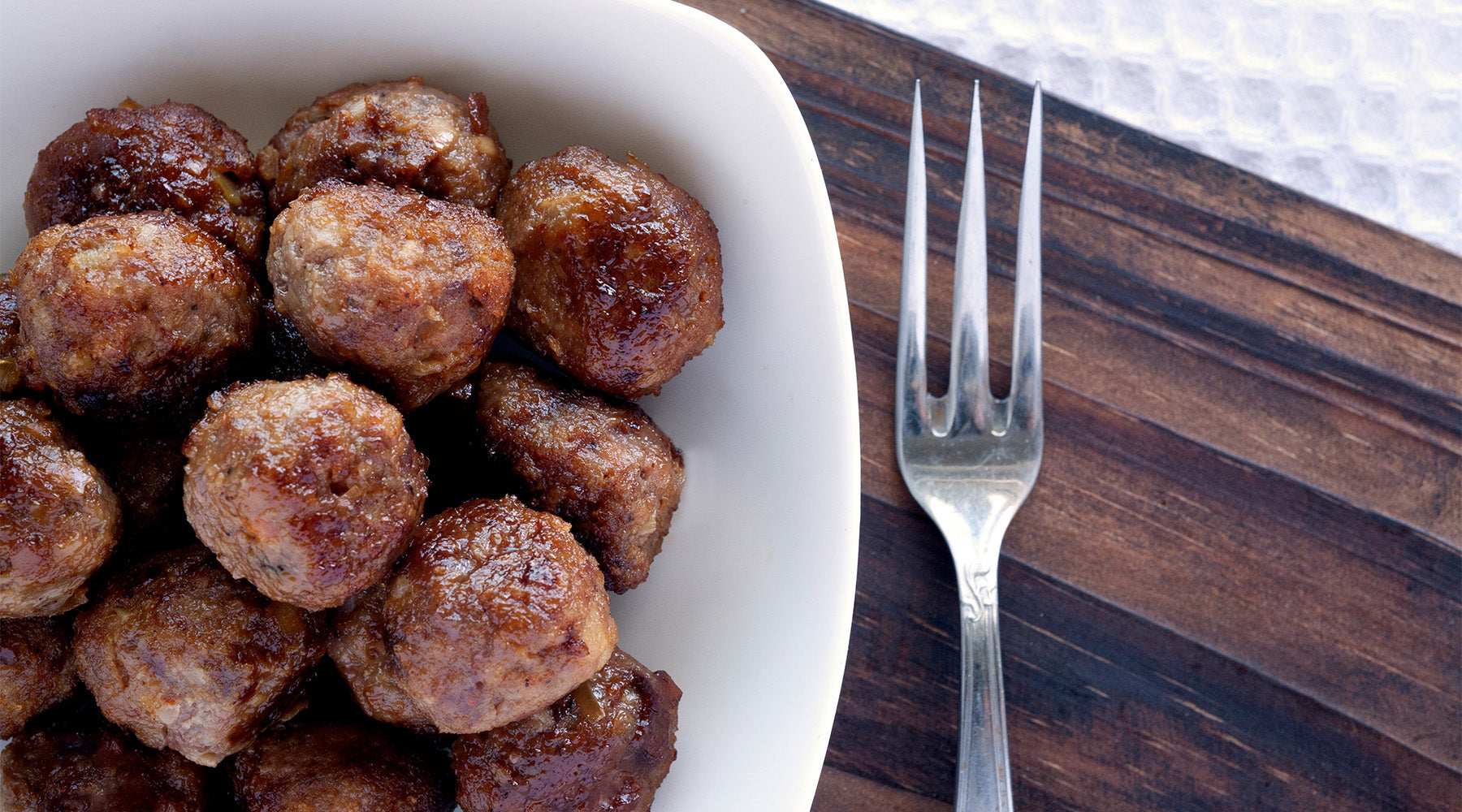 One-Pot Apple Sausage Meatballs in a white bowl on a wood counter top 