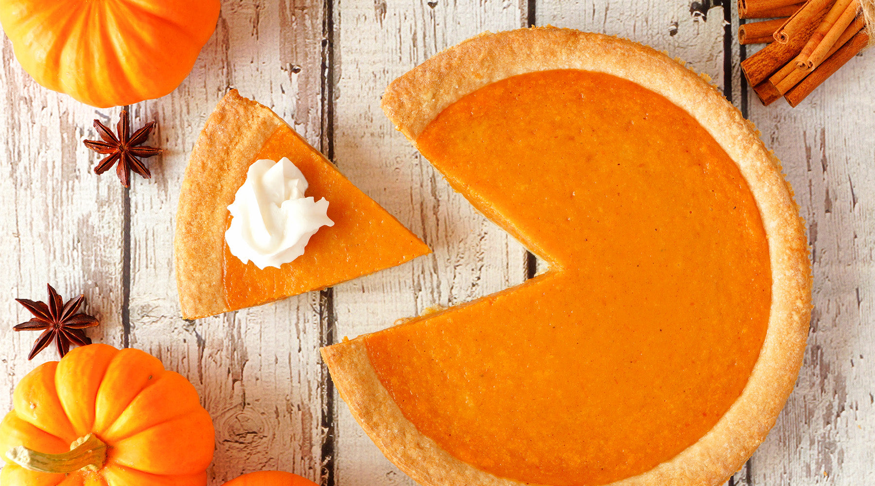 Pumpkin Pie with a slice taken out on a white counter top with fall decorations