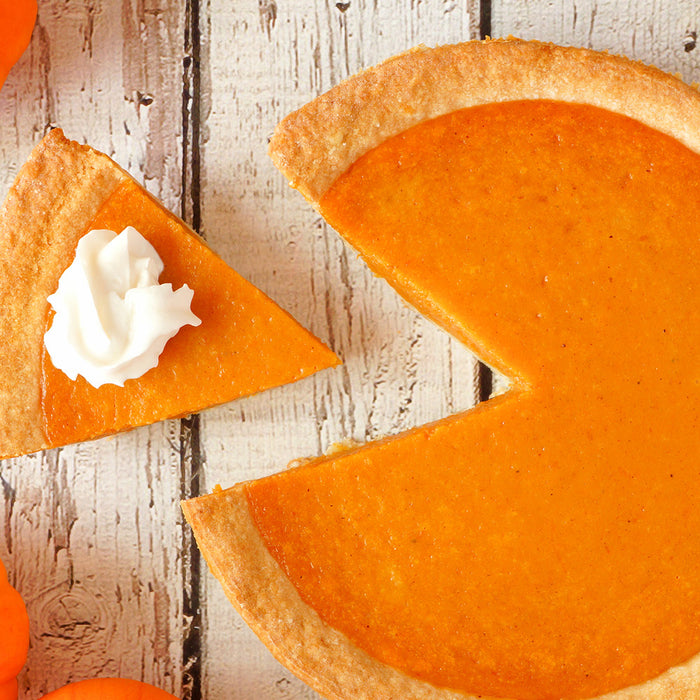 Pumpkin Pie with a slice taken out on a white counter top with fall decorations