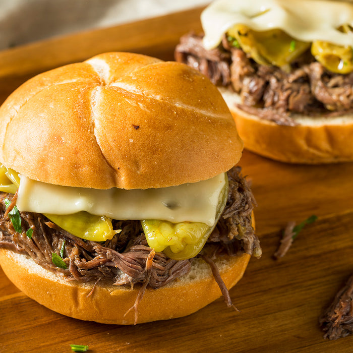 Shredded beef sandwiched in a kaiser roll topped with yellow pepperoncini peppers and cheese