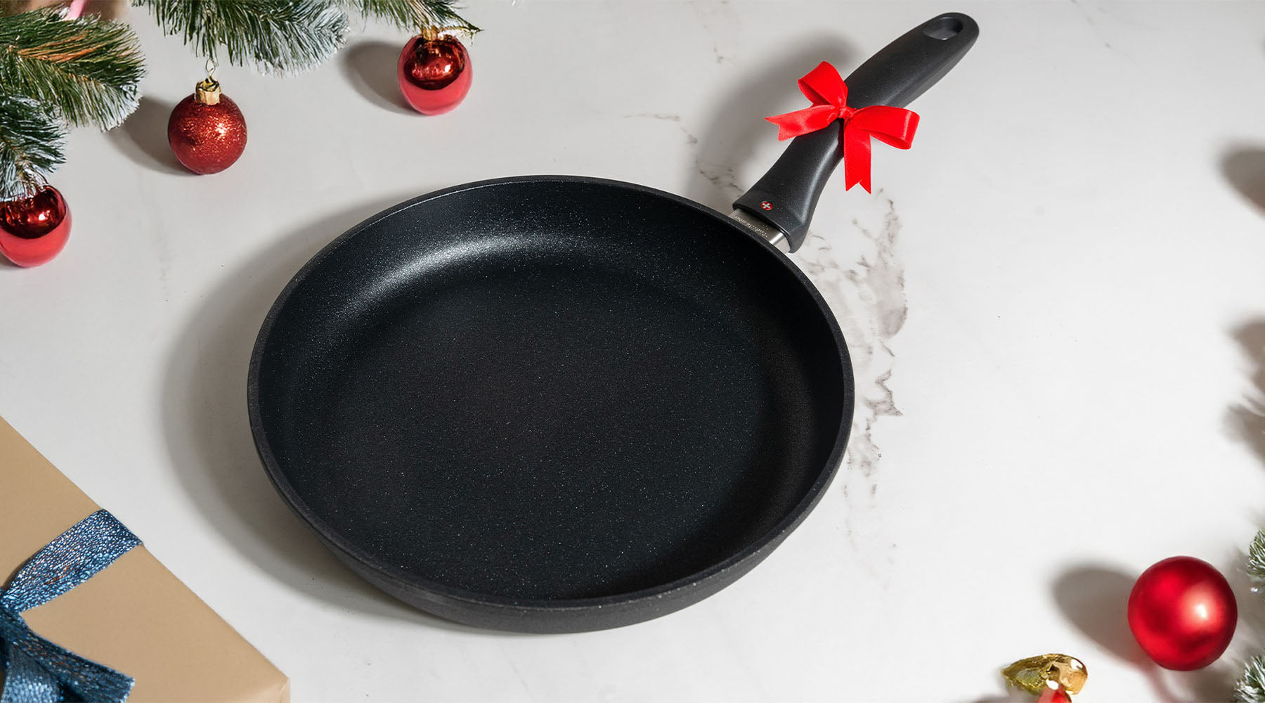 Swiss Diamond fry pan with a bow on the handle surrounded by holiday decorations