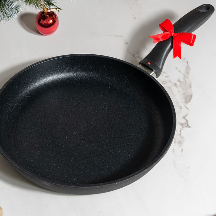 Swiss Diamond fry pan with a bow on the handle surrounded by holiday decorations