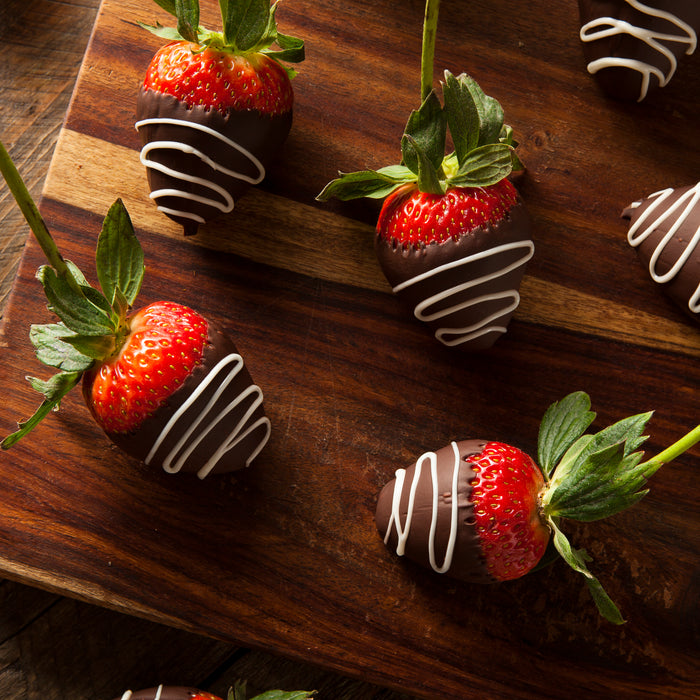 chocolate covered strawberries on a wood cutting board