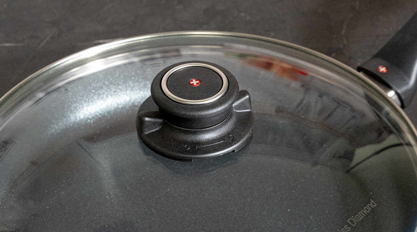 close up view of adjustable black knob attached to a tempered glass cookware lid