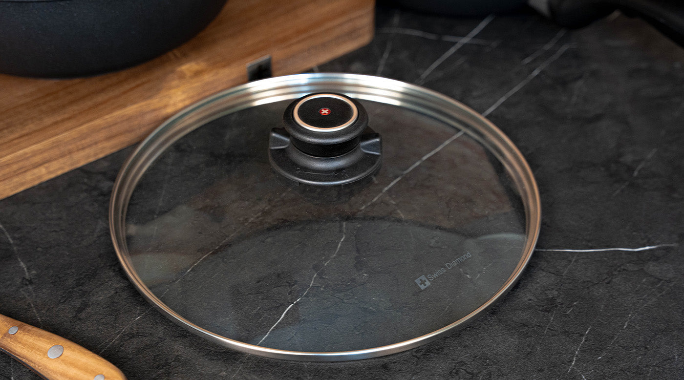 tempered glass lid next to a cutting board on a marble kitchen counter