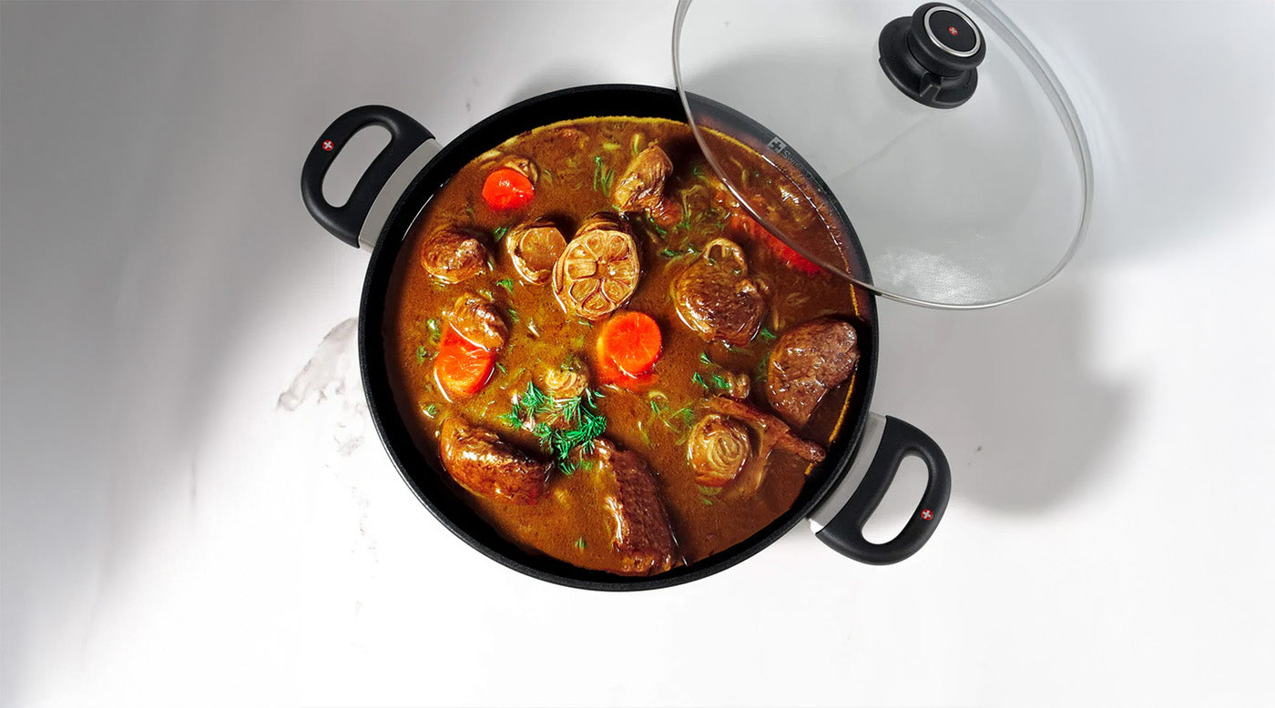 Nonstick Casseroles & Dutch Ovens with food and glass lid on top of a marble kitchen counter