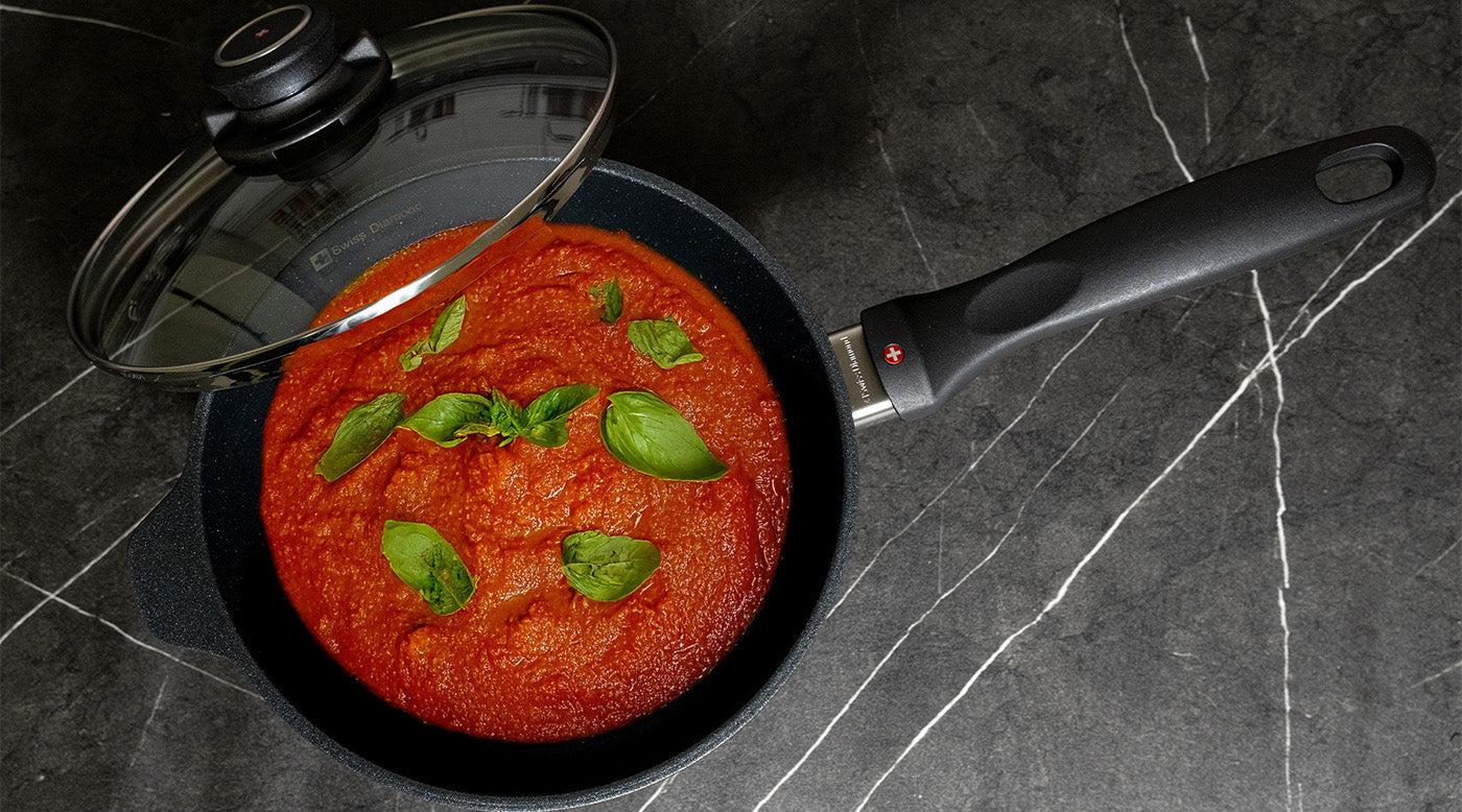 nonstick saucepan or sauce pot with food inside and glass lid on kitchen countertop