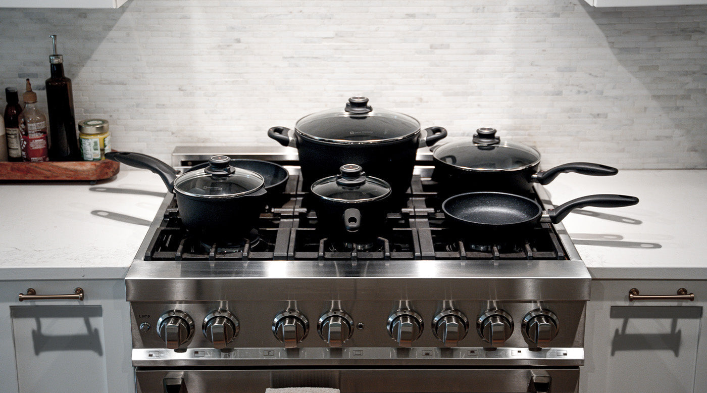 nonstick sets of pots and pans with glass lids on stove top in kitchen