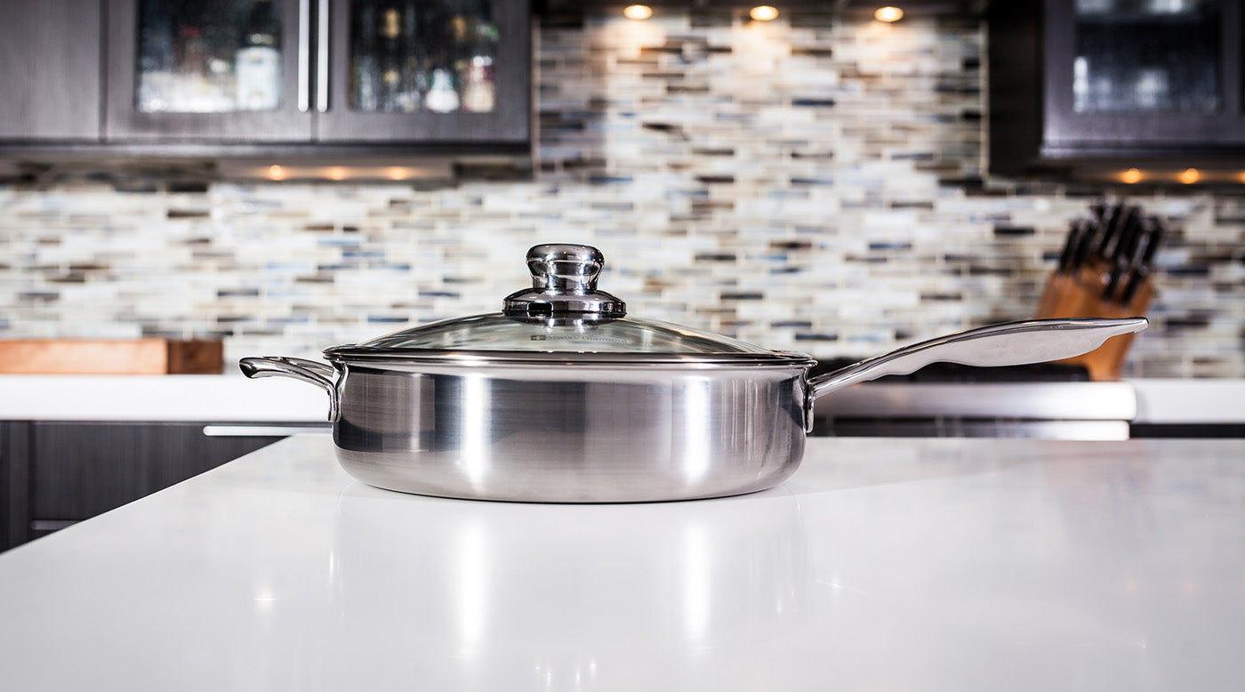 Stainless Steel Sauté Pans side profile view with glass lid on white marble kitchen countertop