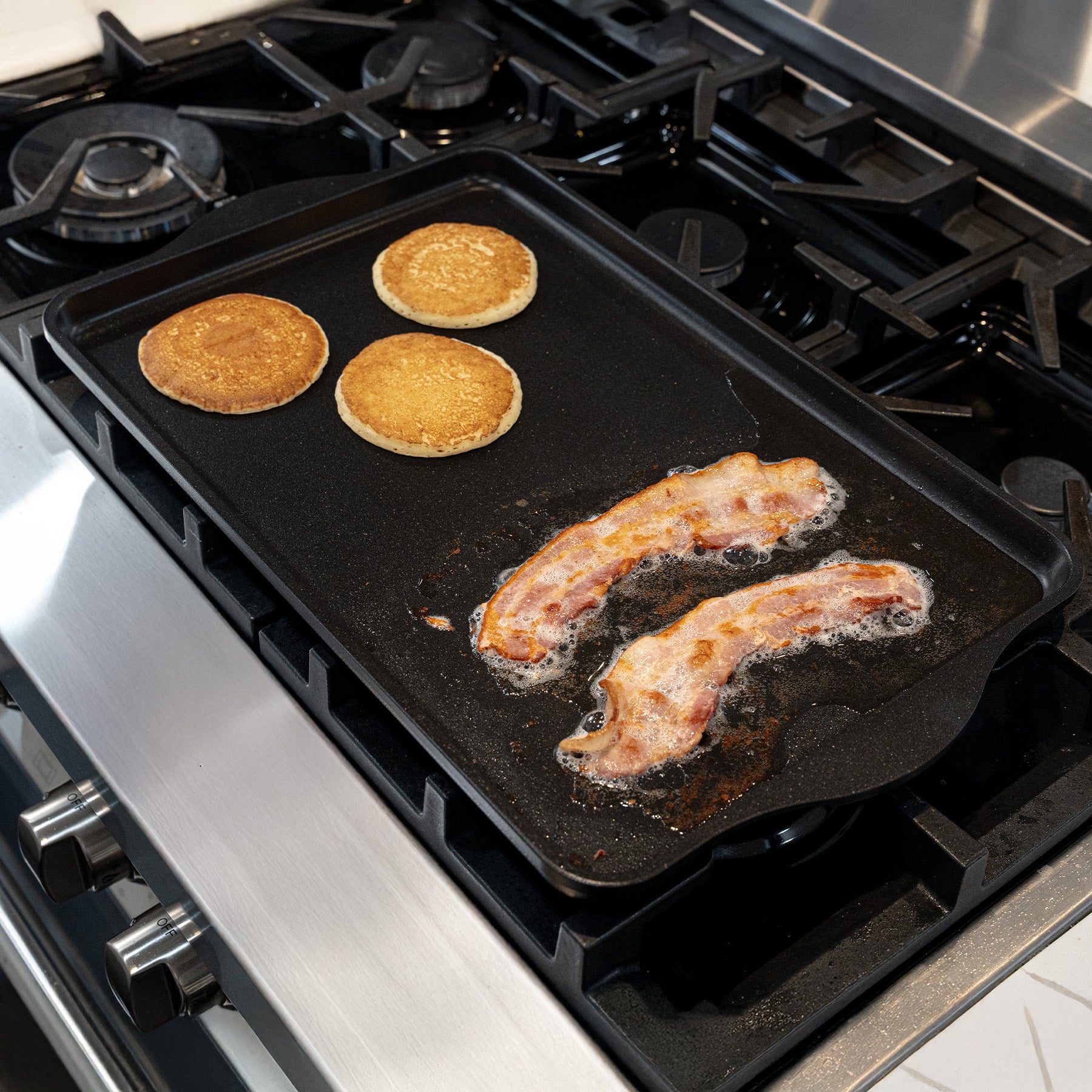 CHD Nonstick 17" x 11" Double-Burner Griddle on gas stove top with food on it