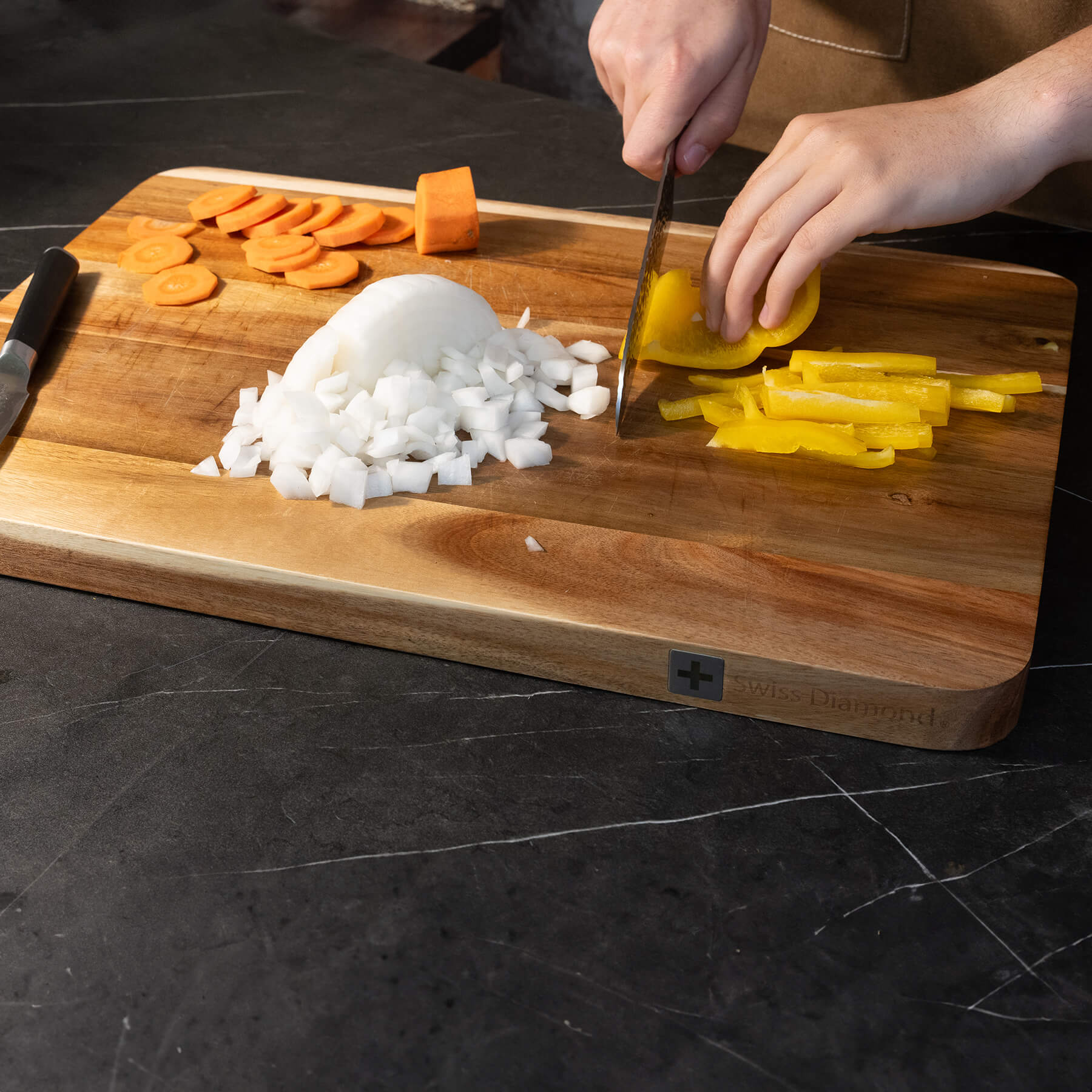 20" Acacia Wood Cutting Board at an angle on counter with food being sliced on surface