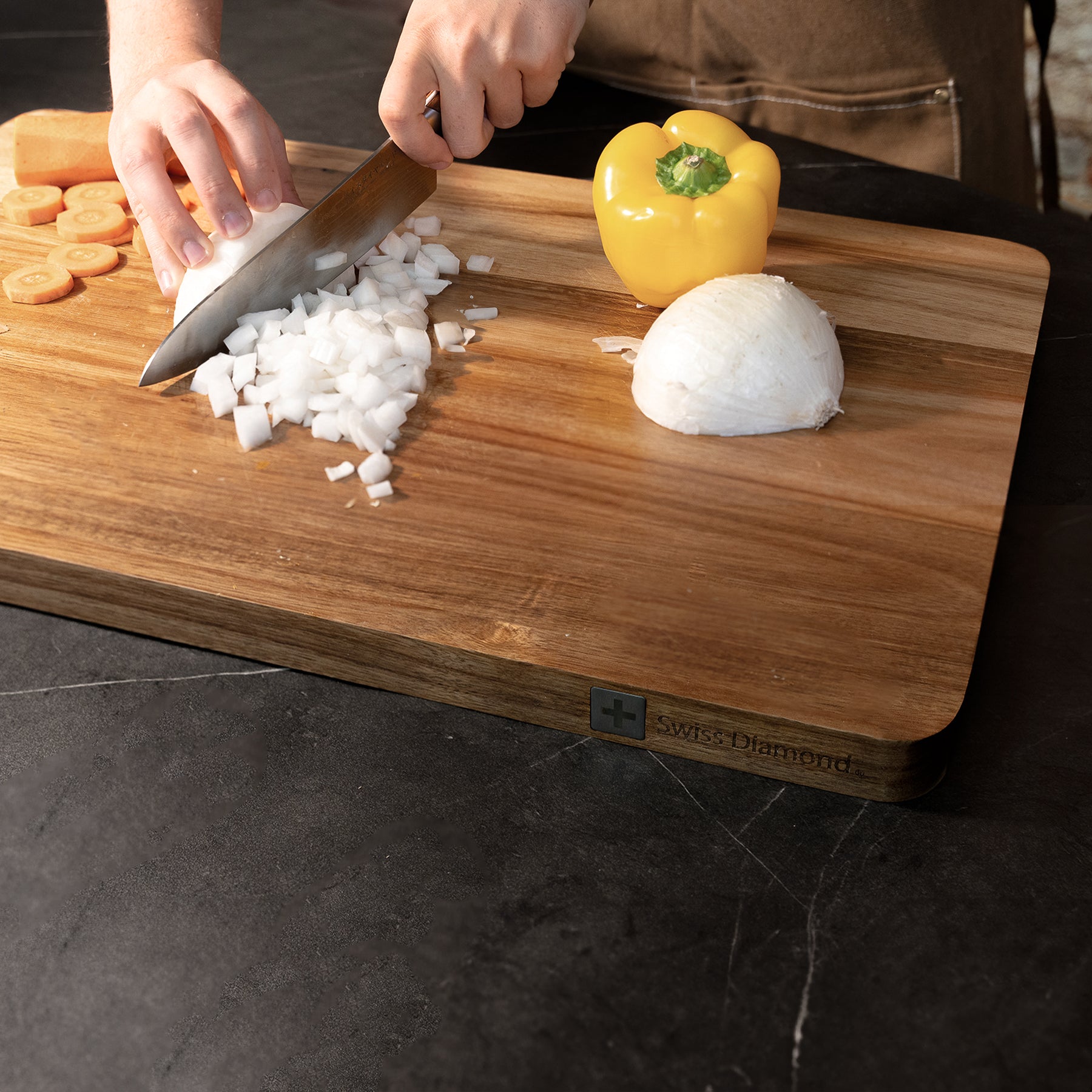 24" Acacia Wood Cutting Board at an angle in use food being chopped on surface