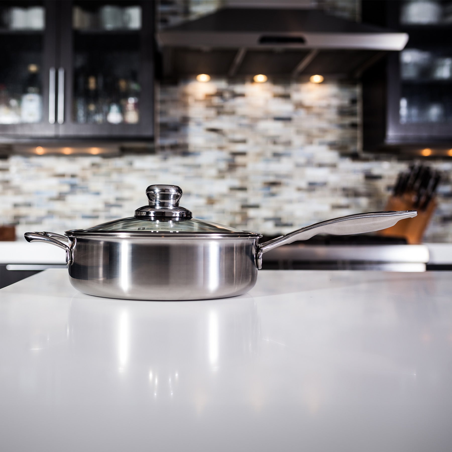 Premium Clad Saute Pan with Glass Lid - Induction in use on kitchen counter - side view