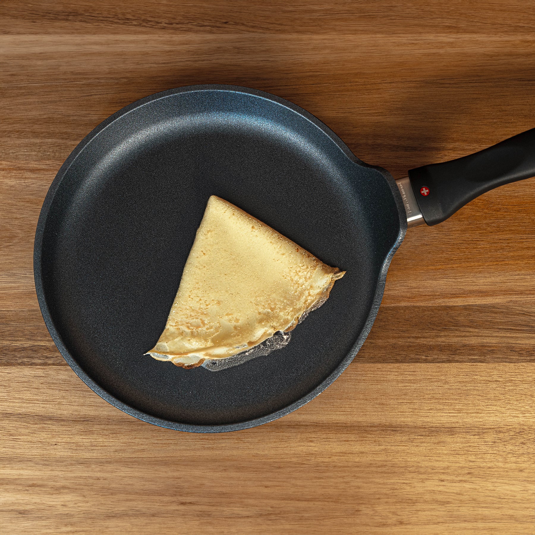 XD Nonstick Crepe Pan top view with food on pan sitting on a wooden table