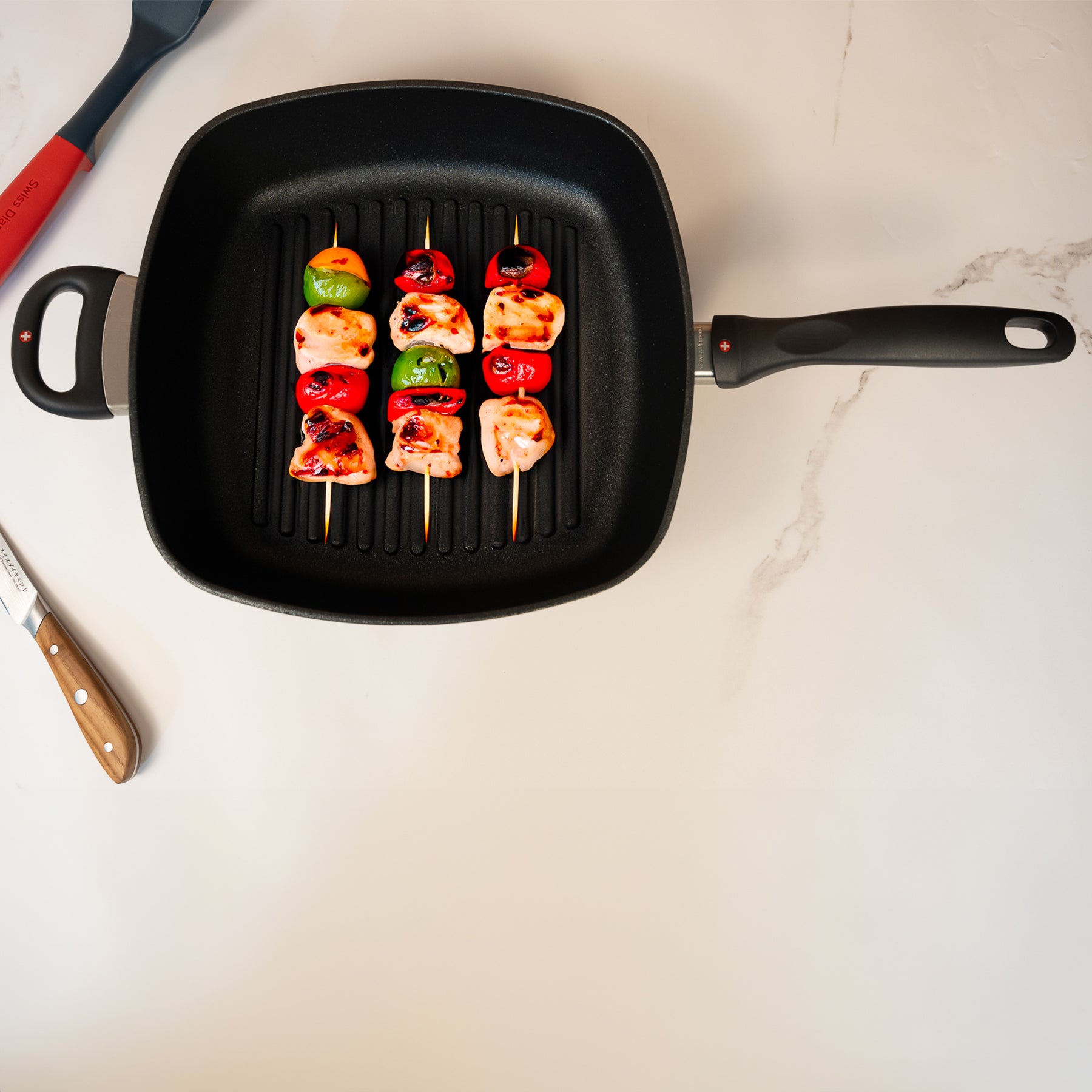 XD Nonstick 11" x 11" Deep Square Grill Pan - Induction in use with kabobs on surface