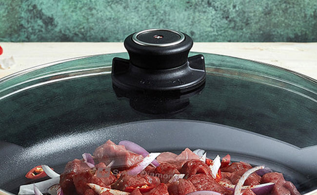 glass lid sitting on top of pan with food inside