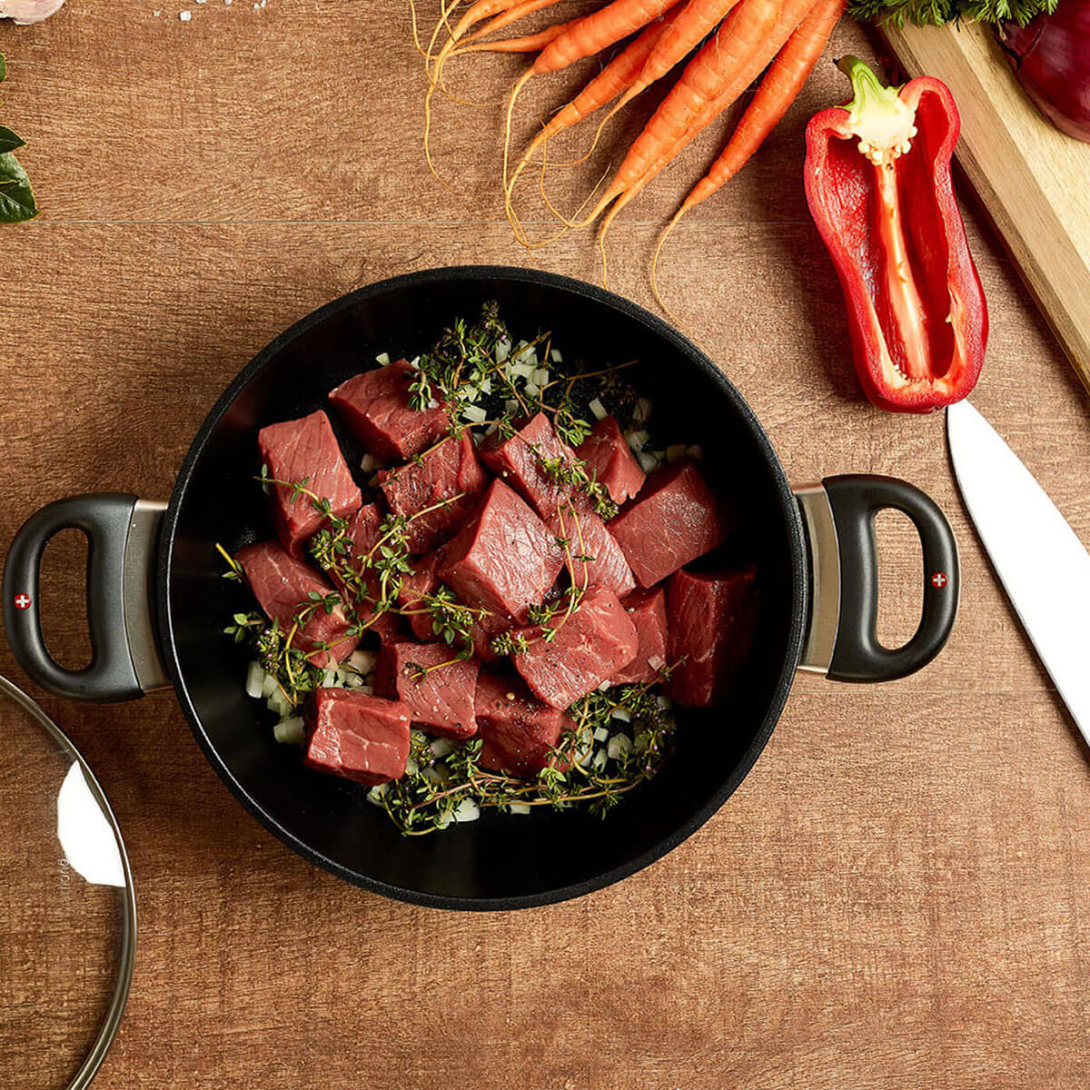 xd stock pot in use with raw beef cubed and fresh herbs on wooden table